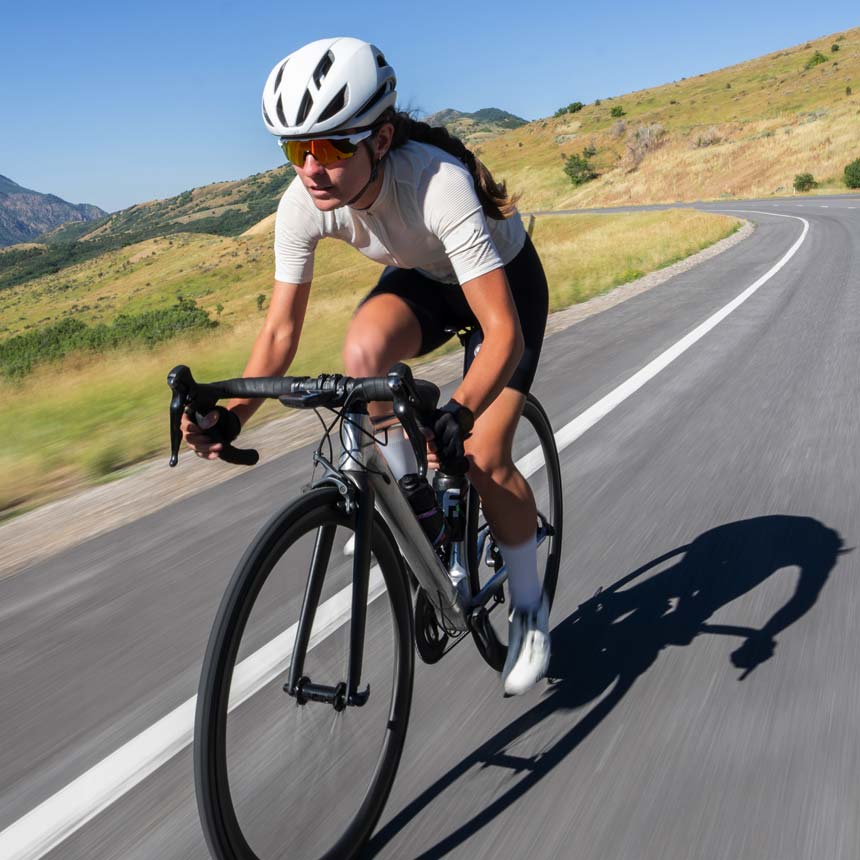 Road cyclist riding along a sunny mountain road